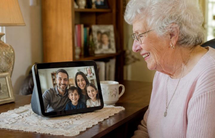 Elderly woman smiling at an Echo Show screen during a video call with family —