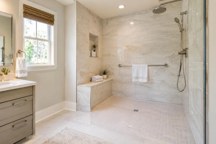 Bright, modern bathroom with a curbless shower, a bench built into the tile, and a brushed-nickel grab bar styled like a towel bar